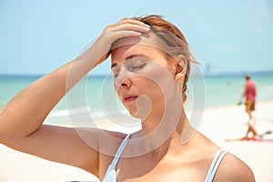 Sunstroke woman on sunny beach. Woman with headache. Hot sun danger. Health problem on holiday