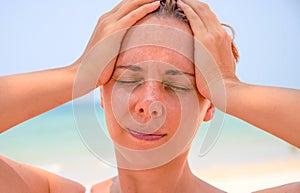 Sunstroke woman on tropical beach. Woman on hot beach with sunstroke. Headache from sun. photo