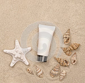 A suntan cream and seashells on sandy background
