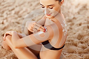 Suntan Lotion. Sexy Young Woman Applying Sunscreen Solar Cream on the beach.Sun Protection.