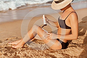 Suntan Lotion. Sexy Young Woman Applying Sunscreen Solar Cream on the beach.Sun Protection. Sun Cream.