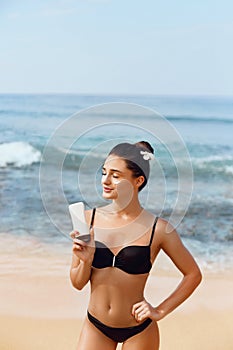 Suntan Lotion. Sexy Young Woman Applying Sunscreen Solar Cream on the beach.Sun Protection. Sun Cream. Skin and Body Care.Girl Hol