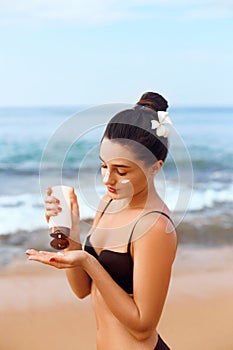 Suntan Lotion. Sexy Young Woman Applying Sunscreen Solar Cream on the beach.Sun Protection.