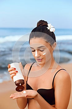 Suntan Lotion. Sexy Young Woman Applying Sunscreen Solar Cream on the beach.