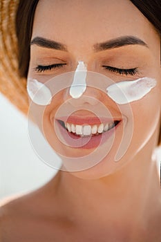 Suntan Lotion Woman Applying Sunscreen Solar Cream on Face.