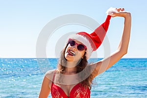 Suntan young woman slim in santas hat and red bathing suit relaxing tropical sand beach. christmas winter vacation holiday concept