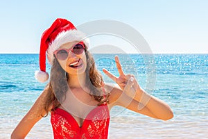 Suntan young woman slim in santas hat and red bathing suit relaxing tropical sand beach. christmas winter vacation holiday concept