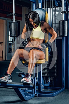 Suntanned fitness female exercising in a gym.