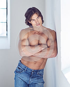 Suntanned muscular male in blue jeans posing.