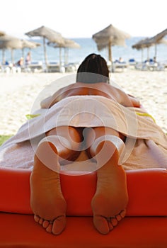 Suntanned woman lying on massage table