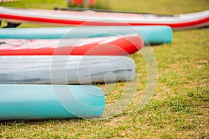 SUP boards lying on the grass by the river, lake or sea