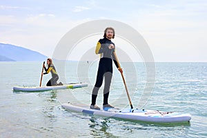 SUP Stand up paddle board couple paddleboarding at sea, on paddleboard on blue water