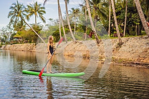 SUP Stand up paddle board woman paddle boarding on lake standing happy on paddleboard on blue water. Action Shot of