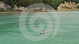 Sup surfer woman rowing on surfboard. Beautiful seascape. Man lying on board