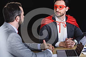 super businessman in mask and cape talking with businessman in office