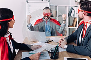 super businessman showing yes gesture to colleagues