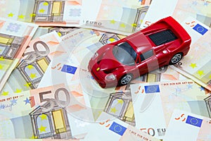 Super car model on pile of 50 EUR banknotes
