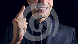 Super close-up of a man in black clothes on a black background. 4k. Slow motion. man clicks his fingers and raises his