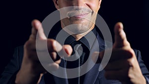 Super close-up of a man in black clothes on a black background. 4k. Slow motion. man points finger at the camera.