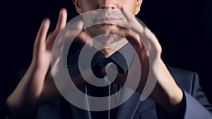 Super close-up of a man in black clothes on a black background. 4k. Slow motion. man shows thumbs up sign.