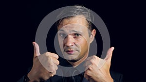 Super close-up of a man in black clothes on a black background. 4k. Slow motion. man shows thumbs up. sign super