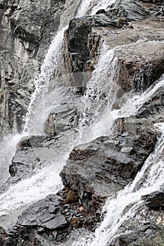 Super contrast and monochrome shot of flowing and foaming water of alpine waterfall over gray granite rocks. Aosta valley, Italy