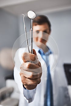 A super dentist uses super tools. Portrait of a young woman holding dental tools in her office.