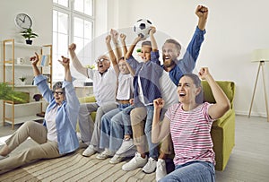 Super excited and happy big multi-generational family watching football match together.