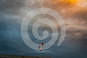 Super flexible woman jumping on the dramatic sky background. Concept of dream and willpower