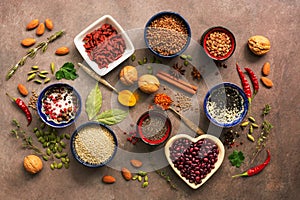 Super food background, a variety of cereals, legumes, spices, herbs, nuts. Various seasonings for cooking on brown background. Top photo