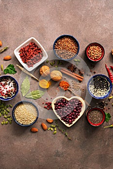 Super food background, a variety of cereals, legumes, spices, seeds,herbs, nuts. Various seasonings for cooking on brown