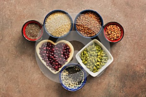 Super food cereals, legumes, seeds on a brown background. Chia, quinoa, beans, buckwheat, lentils, sesame, pumpkin seeds. Top view