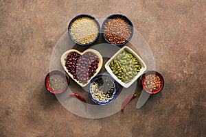 Super food cereals, legumes, seeds and chili peppers on a brown background. Chia, quinoa, beans, buckwheat, lentils, sesame,
