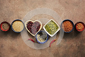 Super food cereals, legumes, seeds and chili peppers on a brown grunge background. Chia, quinoa, beans, buckwheat, lentils, sesame