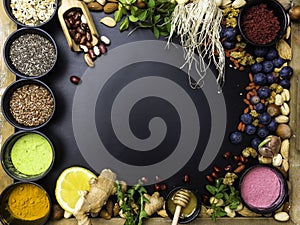 Super food or vegetarian food concept. Seeds, cereals, beans, vegetables, herbs for healthy cooking on black wooden background