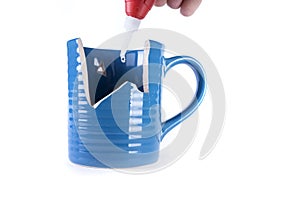 Super glue tube leaking a drop of glue onto a broken mug