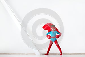 Super hero boy in red boxing gloves and a cape in the wind.