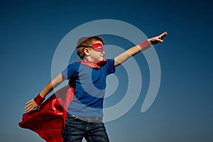 Super hero child boy against blue sky