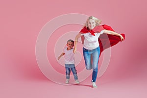 Super mom and her son run forward. Fun family, a young blond woman in a red Cape as superhero