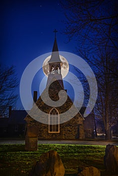 A super moon above the Anglican stone-field church, St. Peter`s of Cookshire-Eaton in Estrie, Quebec, Canada