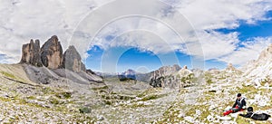 Super Panorama of the mountain ridge of Tre Cime di Lavaredo and resting tourist with his dog