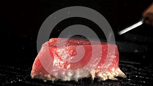 Super slow motion fresh tuna steak is fried in a frying pan with a splash of oil. Filmed on a high-speed camera at 1000