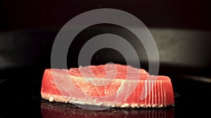 Super slow motion tuna steak is fried in a pan with oil splashes. Filmed on a high-speed camera at 1000 fps.