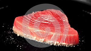 Super slow motion tuna steak is fried in a pan with oil splashes. Filmed on a high-speed camera at 1000 fps.