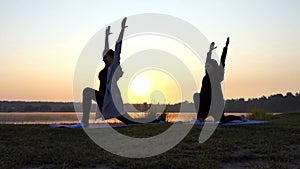 Super Sunset And Women Doing Warrior 2 Yoga Exercise on a Lake Bank