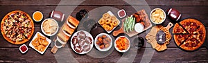 Superbowl or football theme food table scene banner, above view on dark wood