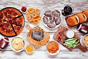 Superbowl or football theme food table scene, top view on white wood