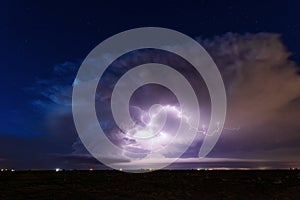 Supercell storm clouds illuminated by lightning strikes