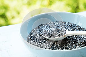 Superfood chia seeds in a wooden spoon in a bowl on the table close-up.
