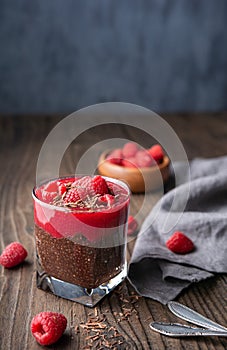 Superfood healthy vegan dessert, dark cocoa chia seed pudding with raspberry puree, topped with fresh berries and chocolate